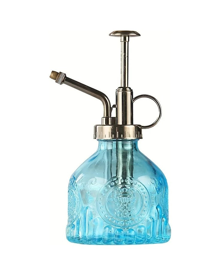 Blue pressed glass plant mister with a bronze-tone pump top, on white