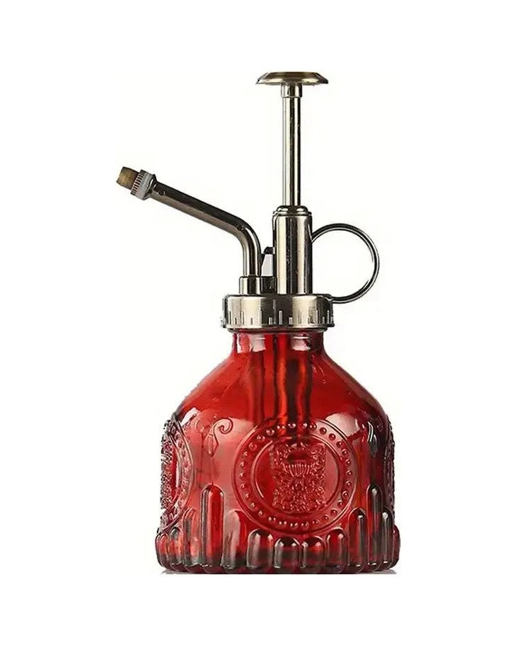 Red pressed glass plant mister with a bronze-tone pump top, on white