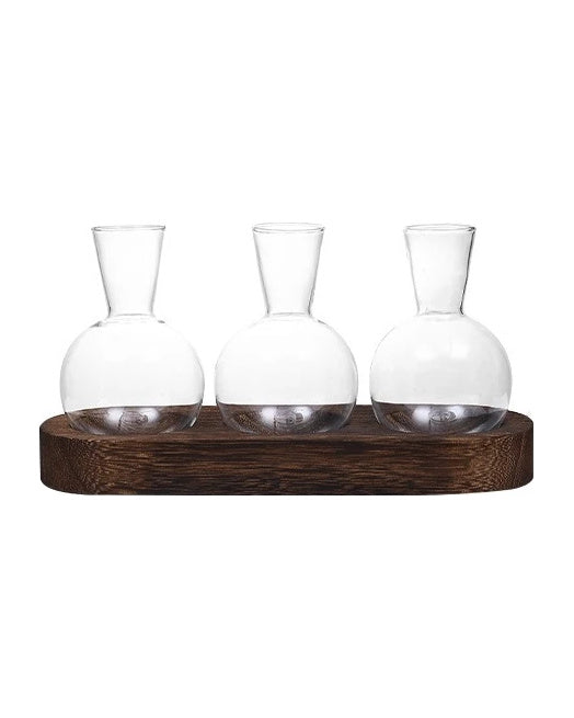 Three round glass bulb vases on a dark wooden tray, on white